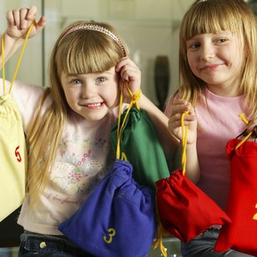 Children holding up the contents of a V&A activity backpack.