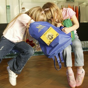 Children delving into a V&A activity backpack in the glass gallery.