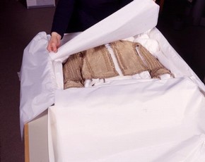 A historic costume stored in an box, with acid-free tissue.